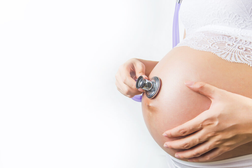 mujer embarazada que usa estetoscopio que examina su bebe su vientre